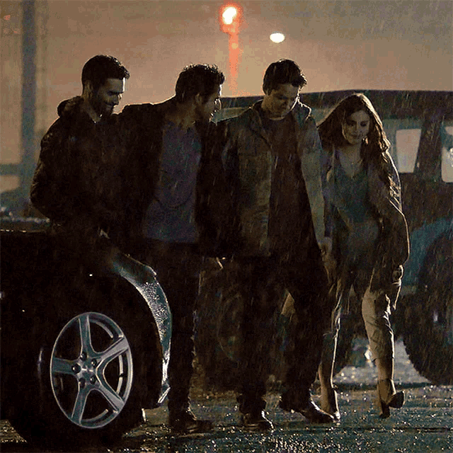 a group of people walking in the rain near a car