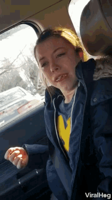 a woman in a car wearing a michigan sweatshirt
