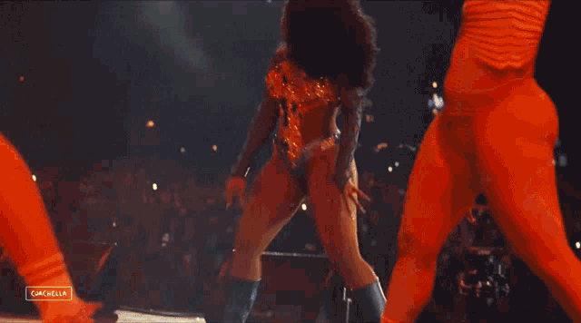 a woman in a bodysuit is dancing in front of a crowd with the words coachella on the bottom right