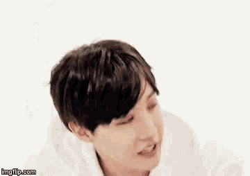 a close up of a young man wearing a white hoodie and making a funny face .