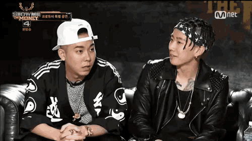 two men are sitting on a couch in front of a sign that says show me money 4