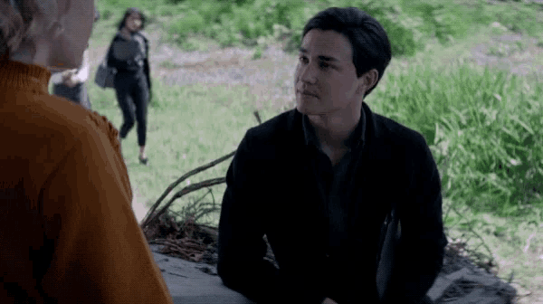 a man in a black jacket sits next to a woman in a red sweater