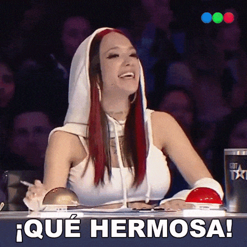a woman with red hair is sitting in front of a sign that says ique hermosa