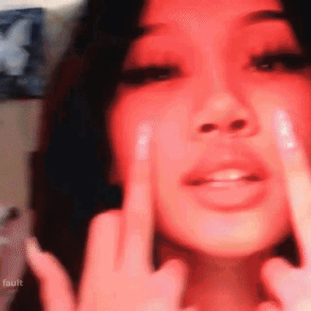 a woman is giving the middle finger to the camera in a blurry picture .