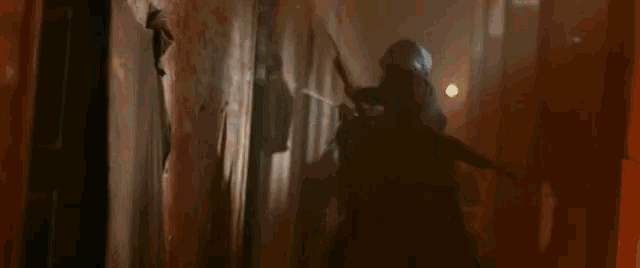 a man in a hood is holding a bow and arrow in his hand .