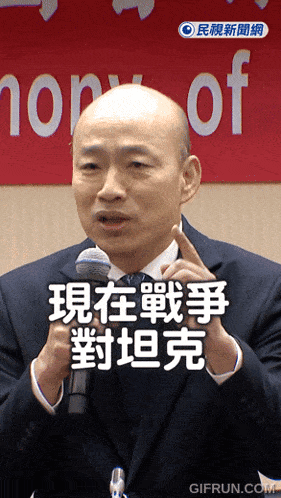 a man in a suit is speaking into a microphone in front of a sign that says ' honor of '