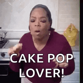 oprah winfrey is eating a piece of cake in a kitchen and saying `` cake pop lover '' .