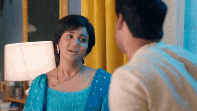 a woman in a blue dress talks to a man