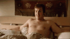 a shirtless man is laying in a bed with his arms outstretched