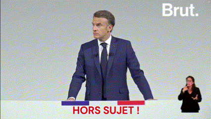 a man in a suit and tie is giving a speech in front of a sign that says hors sujet !