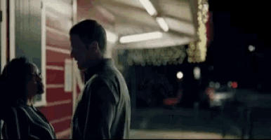 a man and woman are standing in front of a building at night .