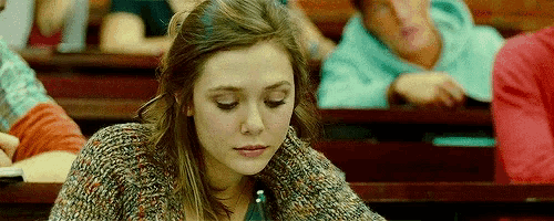 a young woman is sitting at a desk in a lecture hall .