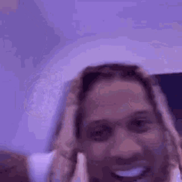 a close up of a person holding a guitar and smiling in a purple room .