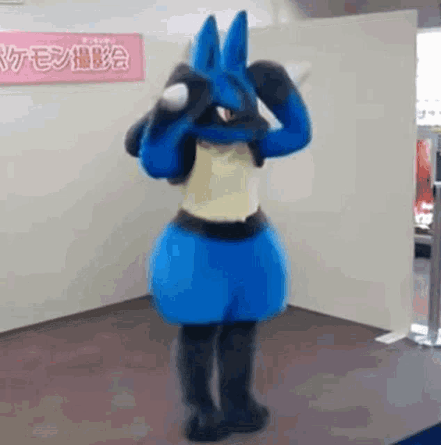 a person in a lucario costume is standing in a room with a sign on the wall .