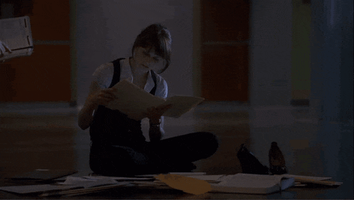 a woman is sitting on the floor looking at a folder