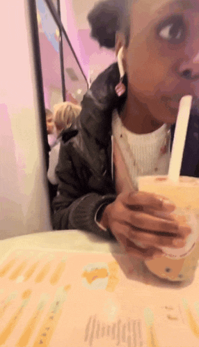a woman sitting at a table drinking a drink with a spoon