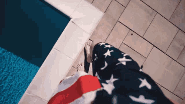 a person standing next to a pool wearing an american flag
