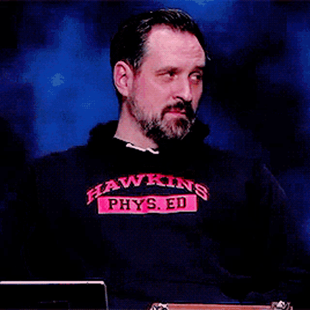 a man wearing a hawkins phys.ed sweatshirt