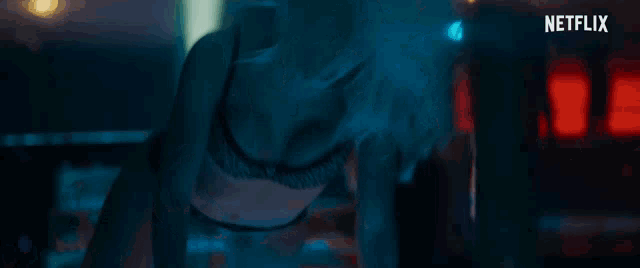 a woman in a black bra is laying on her stomach in a dark room with a netflix logo in the corner