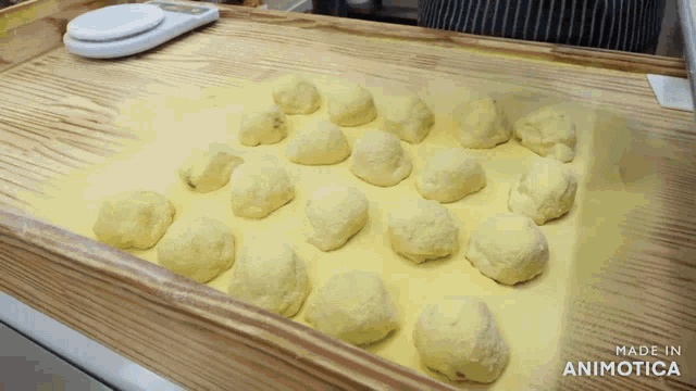 a bunch of balls of dough are on a wooden tray with the words made in animotica on the bottom