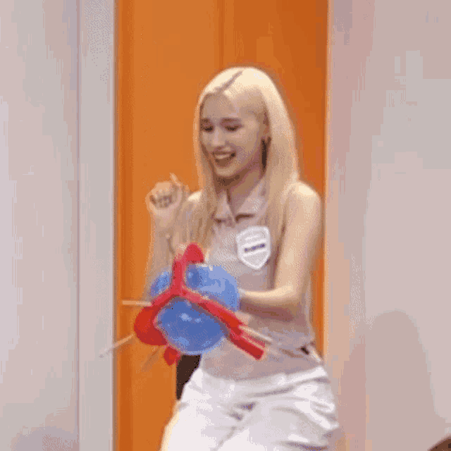 a blonde woman is holding a red and blue balloon in her hands .