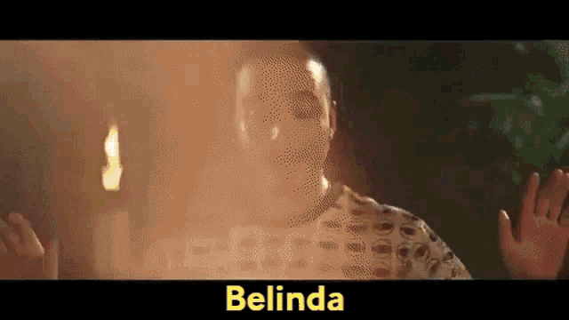 a man is standing in front of a fire with the word belinda on the bottom of the screen .
