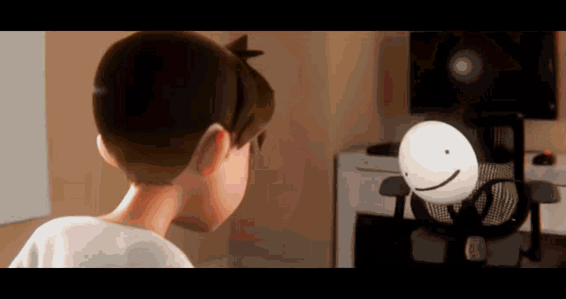 a boy is looking at a cartoon character in a chair with a smiley face on it .