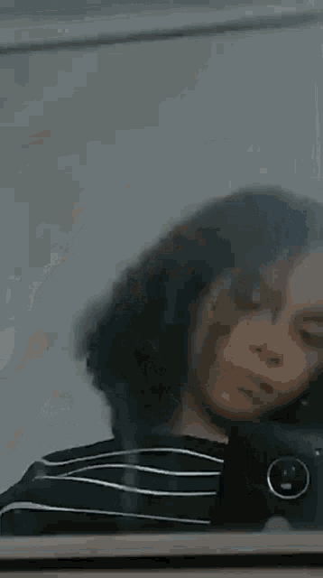 a girl with curly hair is taking a selfie in the mirror