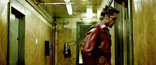 a man in a red jacket is walking down a hallway .