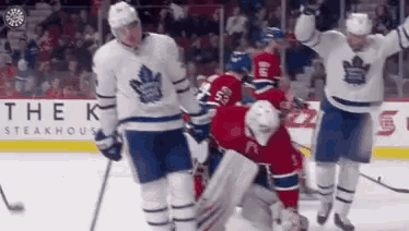 a group of hockey players are standing on the ice and celebrating a goal .