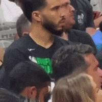 a man with a beard wearing a nike shirt is sitting in a crowd of people