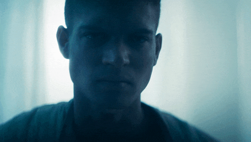a close up of a man 's face with a blue light behind him