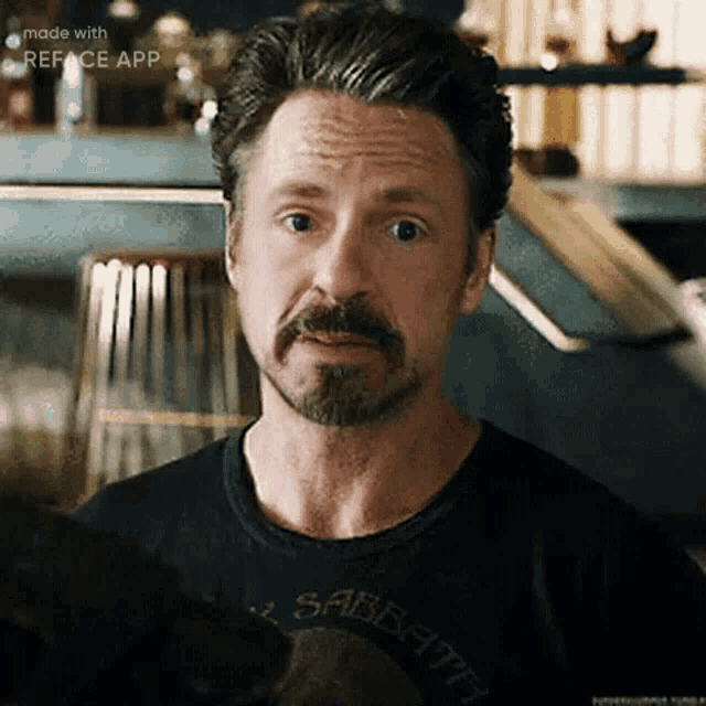 a man with a beard wearing a black shirt that says sabbath
