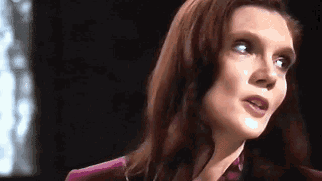 a close up of a woman 's face with a purple shirt on .
