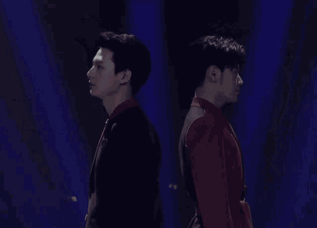 two men are standing next to each other in a dark room