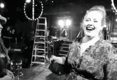 a woman is laughing in a black and white photo while standing in a room .