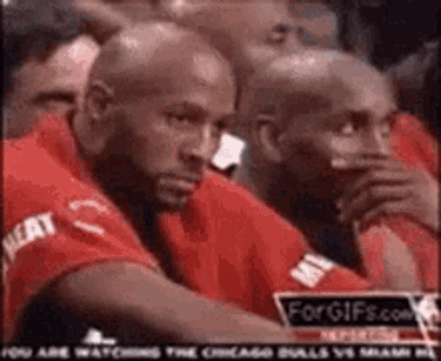 a group of men are sitting in a stadium watching a game .