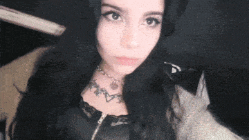 a woman with long black hair and a tattoo on her chest