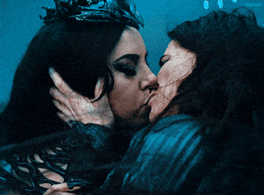 a woman with a crown kisses another woman