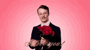 a man in a suit is holding a bouquet of red roses and says " i love you " in gold letters