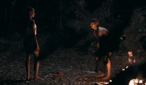 a man and a woman are standing next to each other in front of a fire .