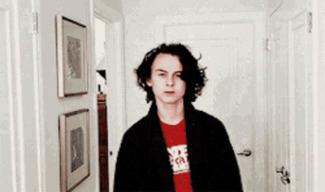a young man is standing in a hallway wearing a red shirt that says ' nf ' on it