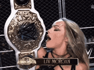 a woman is kissing a wrestling championship belt that says liv morgan on it .