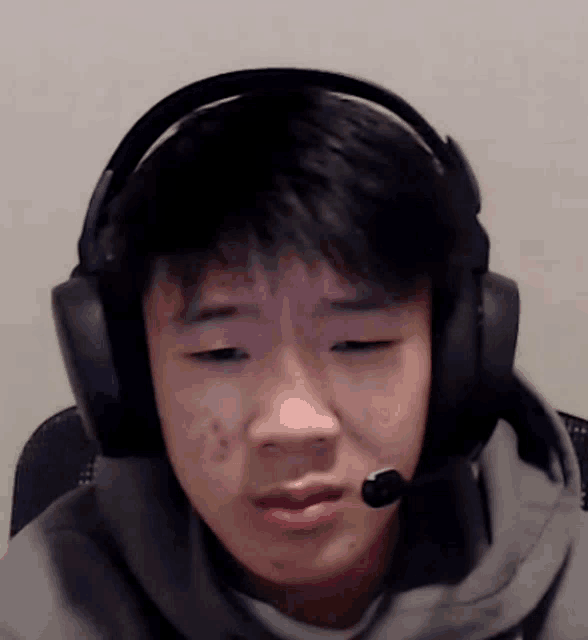 a boy wearing headphones and a microphone looks at the camera