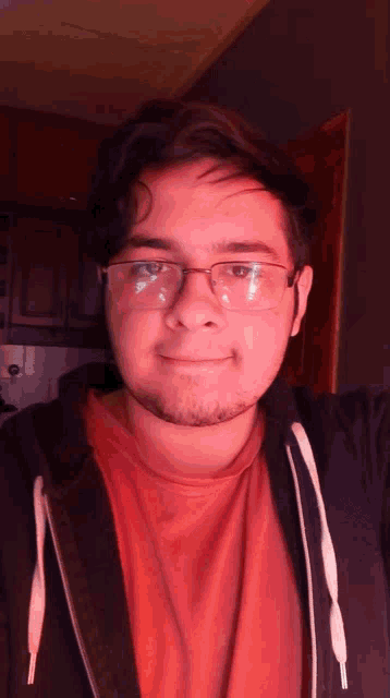 a man wearing glasses and a red shirt is smiling for the camera