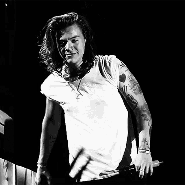a man with long hair is holding a microphone in a black and white photo