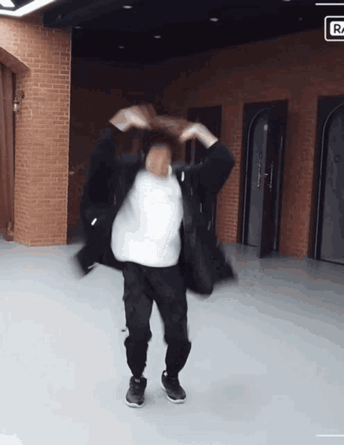 a person is dancing in a room with a brick wall and a sign that says r