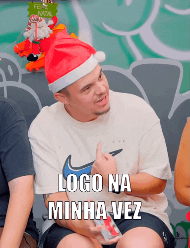 a man wearing a santa hat with the words logo na minha vez on his shirt