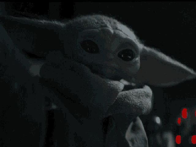 a close up of a baby yoda toy in a dark room .