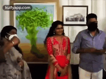 a group of people wearing face masks are standing in front of a painting .